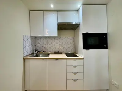 a small kitchen with white cabinets and a sink at Le Laguna - SCLS Locations in Cannes