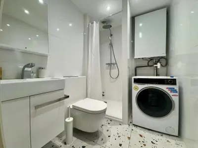 a bathroom with a washing machine in a white bathroom at Le Laguna - SCLS Locations in Cannes