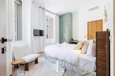 a bedroom with a large white bed and a chair at Les Lucioles 1 - Luxury 1 Bedroom Apartment in Cannes