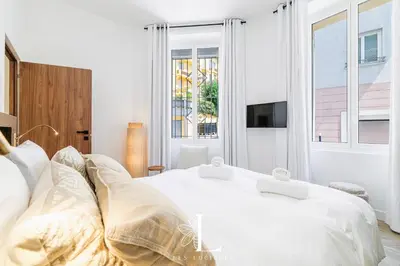 a white bedroom with two beds and a window at Les Lucioles 1 - Luxury 1 Bedroom Apartment in Cannes