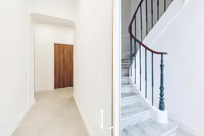 a hallway with white walls and stairs with a wooden door at Les Lucioles 1 - Luxury 1 Bedroom Apartment in Cannes