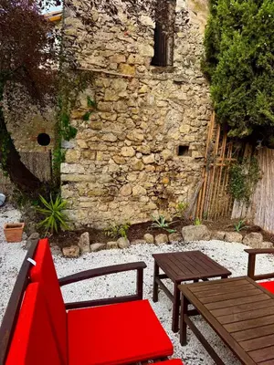 a red bench and a table in front of a stone building at Large duplex with garden in historic house in Le Cannet