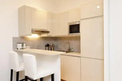 a white kitchen with white cabinets and white stools at Appartement centre-ville à 5 min du palais des festivals in Cannes