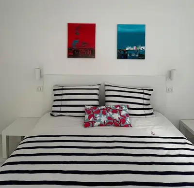 a bedroom with a black and white bed with two pillows at La petite MAISON BLANCHE CANNES in Cannes