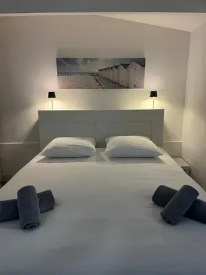 a large white bed with two blue pillows on it at La petite MAISON BLANCHE CANNES in Cannes