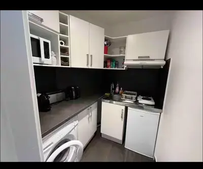 a small kitchen with white cabinets and a sink at Terrasse Clim Wifi Parking 10 min à pieds de la Croisette in Cannes
