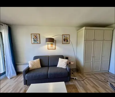 a living room with a blue couch and a cabinet at Terrasse Clim Wifi Parking 10 min à pieds de la Croisette in Cannes