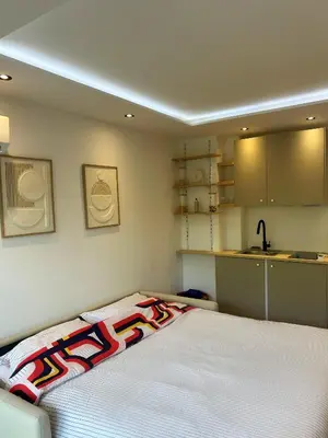 a bedroom with a white bed with colorful pillows on it at Charmant studio avec grande terrasse in Cannes