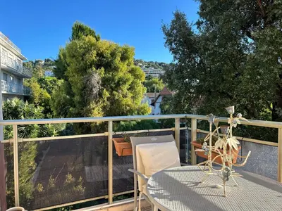 a balcony with a table and chairs and trees at Cozy Cannes Studio - 12 Min Walk To The Beach - Free Parking in Cannes