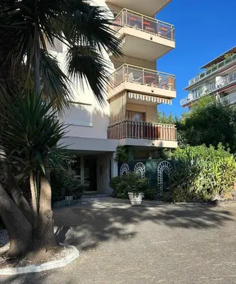 a building with a palm tree in front of it at Cozy Cannes Studio - 12 Min Walk To The Beach - Free Parking in Cannes