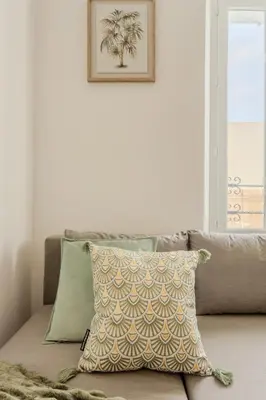 a pillow on a couch with a picture on the wall at Brise de Sauge 1BR cosy clim, proche Palais in Cannes