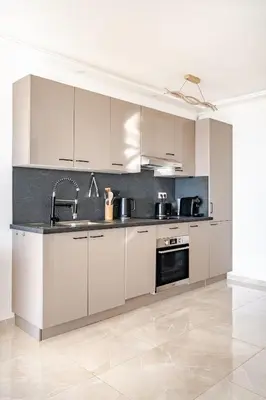 a large kitchen with white cabinets and appliances at Luxury Apartment with Sea View and Private Beach Access in Cannes