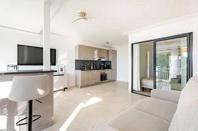 a white living room with a couch and a kitchen at Luxury Apartment with Sea View and Private Beach Access in Cannes