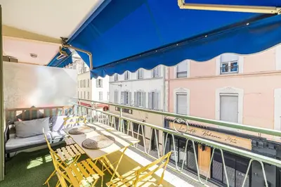 a balcony with a table and chairs and a blue awning at 13 PRAD - Renovated apartment for 3 travelers near Croisette in Cannes