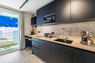 a kitchen with black cabinets and a large window at 13 PRAD - Renovated apartment for 3 travelers near Croisette in Cannes