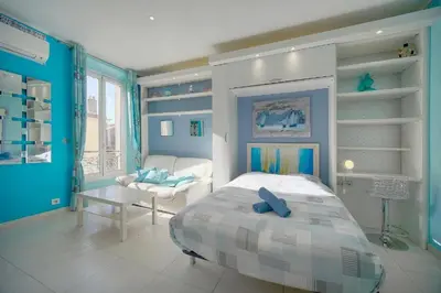 a bedroom with blue walls and a bed and a couch at Studio Cannes Centre 2 min from La Croisette in Cannes