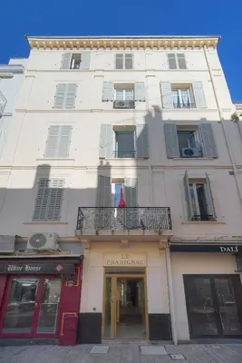 a tall white building with a balcony on a street at Studio Cannes Centre 2 min from La Croisette in Cannes