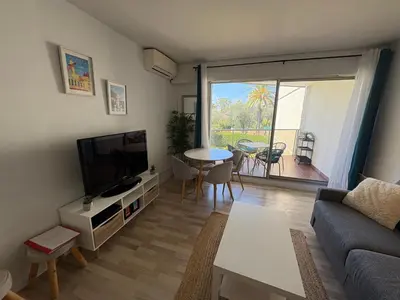 a living room with a couch and a tv and a table at Studio lumineux, terrasse, clim, parking, centre ville in Cannes