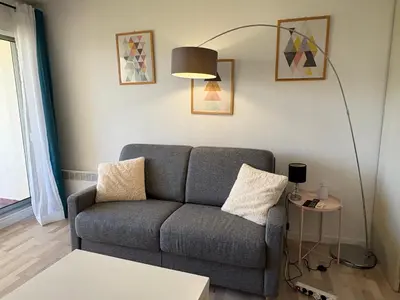a living room with a couch and a lamp at Studio lumineux, terrasse, clim, parking, centre ville in Cannes