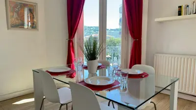 a dining room with a glass table and white chairs at Scène & Palmiers - Cannes in Cannes