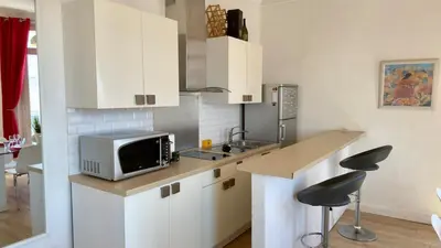 a kitchen with white cabinets and a microwave on a counter at Scène & Palmiers - Cannes in Cannes