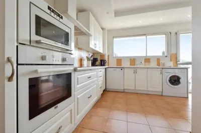 a large kitchen with white cabinets and appliances at Apartment Near Beach With Sea View 2 Terraces! in Cannes