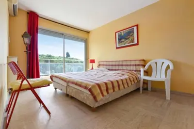 a bedroom with a bed and a chair and a window at Apartment Near Beach With Sea View 2 Terraces! in Cannes