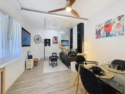 a living room with a couch and a ceiling fan at Studio l'Atelier – Parking & Beaches 15 min Walk in Cannes