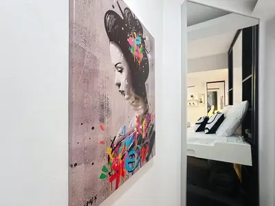 a painting of a woman on a wall next to a bed at Studio l'Atelier – Parking & Beaches 15 min Walk in Cannes