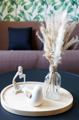 a table with a tray with a glass vase with feathers at Le Nova - 2 chambres, Parking privé, Centre ville in Cannes