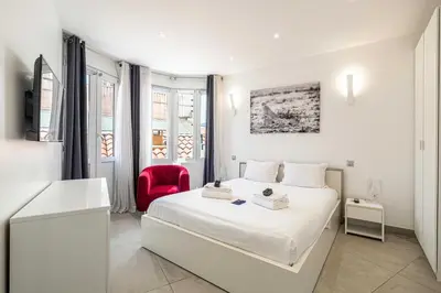 a white bedroom with a bed and a red chair at Charming flat - AC - 2BR - 6P - Cannes in Cannes