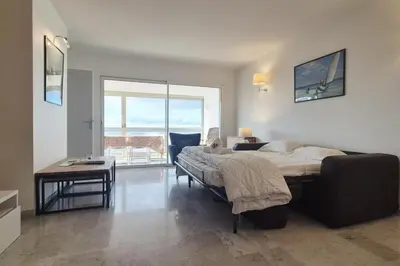 a bedroom with a bed and a table and a window at Beautiful 2-bedroom apt - sea and city view in Cannes