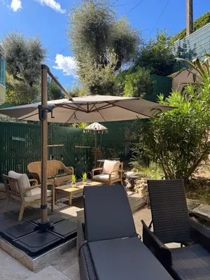 a patio with a table and an umbrella and chairs at Les alizés Cannes in Cannes