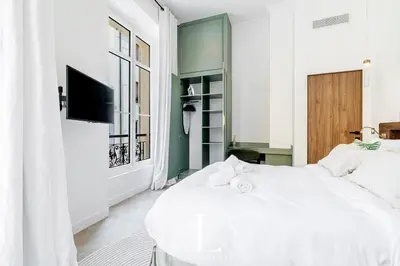 a white bedroom with a white bed and a television at Les Lucioles 4- Luxury 1 Bedroom Apartment in Cannes