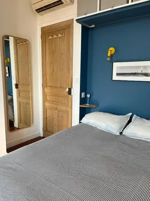 a blue bedroom with a bed and a wooden door at Elégant appartement 2 pièces centre Cannes Croisette plages in Cannes