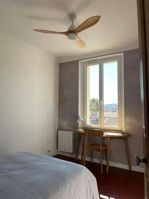 a bedroom with a ceiling fan and a table and a window at Elégant appartement 2 pièces centre Cannes Croisette plages in Cannes