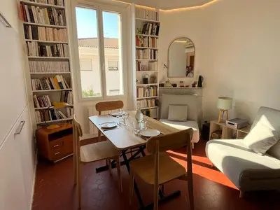a dining room with a table and a living room with a window at Elégant appartement 2 pièces centre Cannes Croisette plages in Cannes