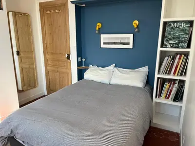 a blue bedroom with a bed and a book shelf at Elégant appartement 2 pièces centre Cannes Croisette plages in Cannes