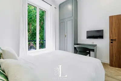 a white bedroom with a bed and a window at Les Lucioles 5- Luxury 2-Bedroom Apartment in Cannes