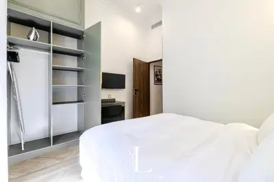 a white bedroom with a bed and a television at Les Lucioles 5- Luxury 2-Bedroom Apartment in Cannes