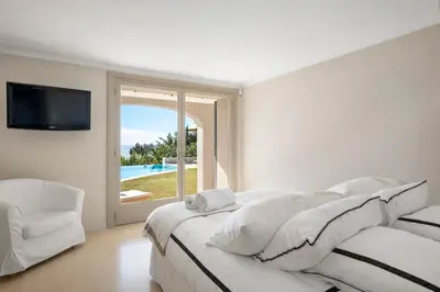 a white bedroom with a large bed and a tv at REF 2138 - Cannes - Villa sea view in Cannes
