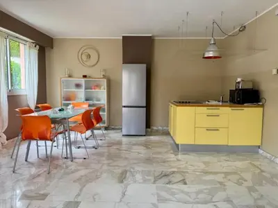 a kitchen with a table and chairs and a refrigerator at The Noailles - Lovely flat with swimming pool five minutes from the beach in Cannes