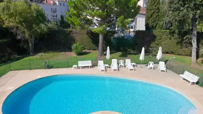 a swimming pool with lounge chairs and umbrellas at The Noailles - Lovely flat with swimming pool five minutes from the beach in Cannes