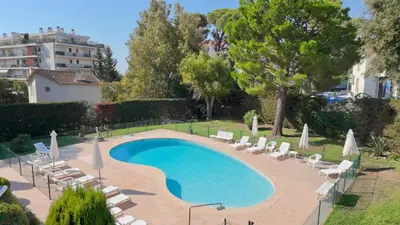 a swimming pool with chairs and umbrellas and a building at The Noailles - Lovely flat with swimming pool five minutes from the beach in Cannes