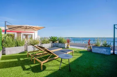 a patio with a table and an umbrella and the ocean at REF 2005 Cannes Center Appartment for rent in Cannes
