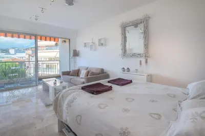 a white bedroom with a bed and a couch at Wdf studio in the heart of Cannes! in Cannes