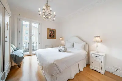 a white bedroom with a large white bed and a chandelier at Truly amazing 3 bedrooms Cannes center!! in Cannes