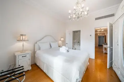 a white bedroom with a white bed and a chandelier at Truly amazing 3 bedrooms Cannes center!! in Cannes