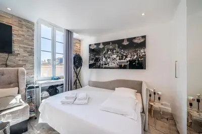 a bedroom with a white bed and a large window at Beautiful studio rue d'Antibes in Cannes