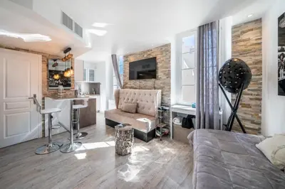 a living room with a bed and a kitchen with a counter at Beautiful studio rue d'Antibes in Cannes